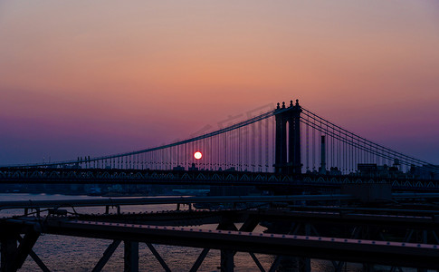 黄昏时分，初升的太阳穿过曼哈顿大桥的绳索