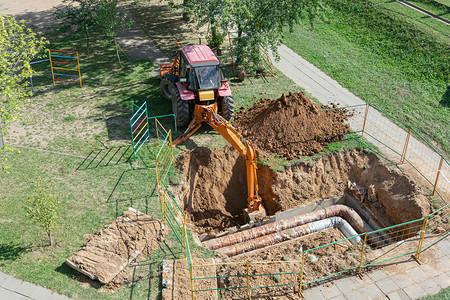 挖坑摄影照片_明斯克，白俄罗斯 — 09/12/2018：拖拉机挖坑修复钻孔