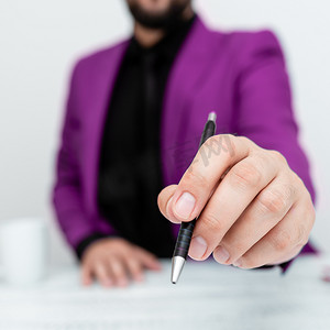 穿着粉色西装的男模特坐在白桌旁，用笔指着重要信息。
