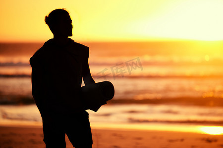 日落、剪影和在海滩上准备训练的瑜伽垫男子。