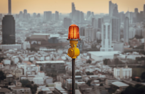 高层建筑屋顶安装的红色障碍灯灯笼，确保飞行安全，并在城市景观背景下警告飞机的危险。