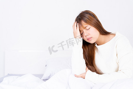 疼痛摄影照片_在床上醒来后患有头痛的年轻女子。