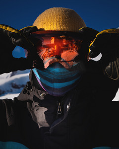 滑雪护目镜摄影照片_男子滑雪护目镜的特写镜头与雪山的倒影。