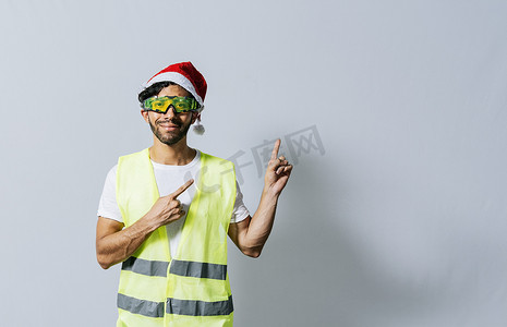建筑工人劳动者摄影照片_有指向广告的圣诞节帽子的建筑工人。