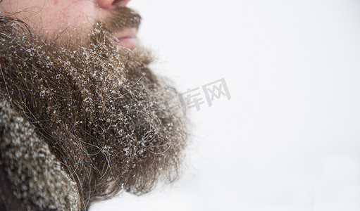大嘴人摄影照片_大胡子的男人在下雪的天气在雪地里的街道上。