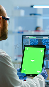 男医生在配备现代设备的实验室中拿着带绿屏的平板电脑