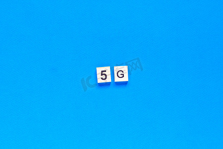 五g摄影照片_5 G. 五个 G，用木制字母写在蓝色背景上。