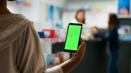 显示屏模板摄影照片_女客户在药房手持带绿屏显示屏的智能手机