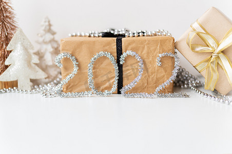2022 年新年快乐。节日的金色装饰 — 一棵树、一份礼物、一颗星星、金属丝。