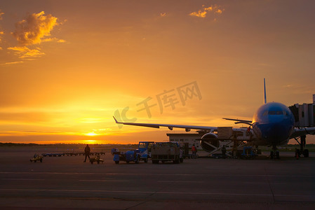 黎明时分，机场地勤人员在一架商用飞机上装载货物和行李。