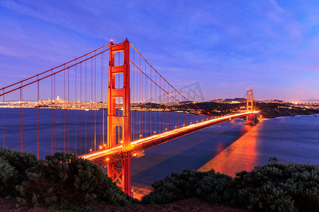 sfo摄影照片_金门大桥上的车灯模糊，旧金山在夜间亮起