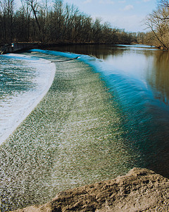 水泡沫水花摄影照片_快速流动的水在冬季前冲过人造水坝