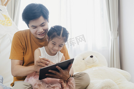 小女孩和年轻的父亲正在享受一起使用平板电脑。
