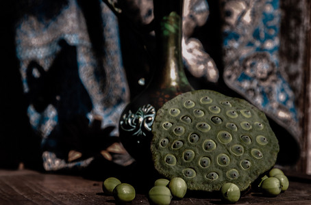 古董雕刻铁壶或旧木椅上的花瓶前新鲜的绿色莲子荚。