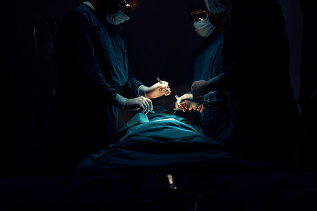 手术室中的病人摄影照片_手术团队在无菌手术室对病人进行手术。