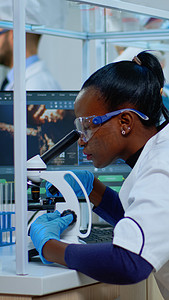 黑人女化学家在显微镜下分析病毒反应