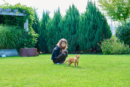 后院草坪上有猫的青春期前女孩