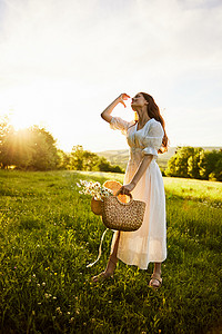 一位穿着浅色夏装的美女站在洋甘菊田里，手里拿着一篮花