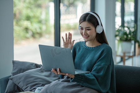 在家工作的年轻亚洲女性在笔记本电脑上工作，同时坐在家里拿着咖啡杯 早安生活方式概念