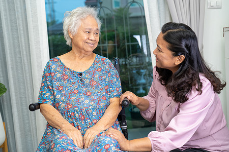 在护理医院病房帮助和照顾坐在轮椅上的亚洲老年或老年老妇人患者，健康强大的医疗理念