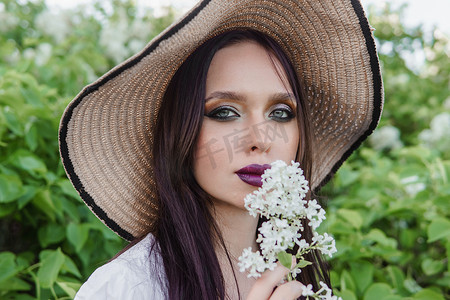 时尚绿色植物摄影照片_一个黑头发的时尚女孩，夏天淡紫色色调的春天肖像。