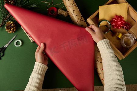 顶视图女人的手推出礼品纸，同时选择包装装饰材料。