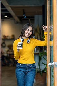 现代咖啡店里拿着一杯咖啡的亚洲年轻女性