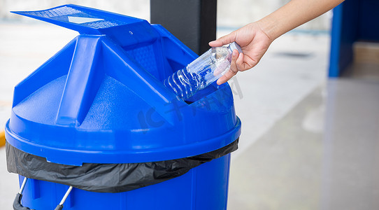 特写女性手将空塑料水瓶扔进回收箱