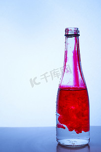 菜单黑金摄影照片_浅色背景中玻璃瓶中与水混合的红墨水