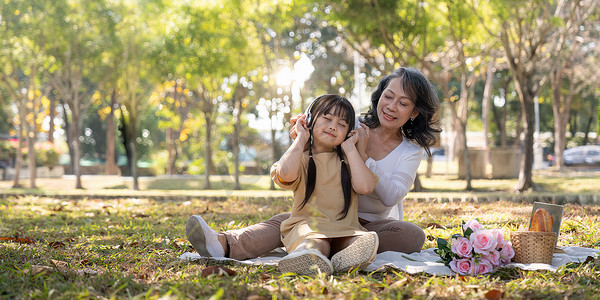 快乐的亚洲祖母和她可爱的孙女一起在公园野餐。