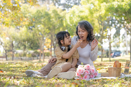 快乐的亚洲祖母和她可爱的孙女一起在公园野餐。