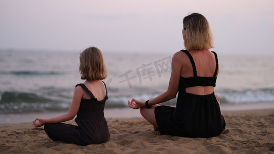 有女儿在海滩上的女人正在做瑜伽
