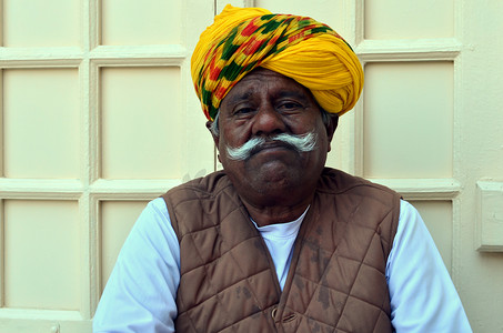 焦特布尔，印度拉贾斯坦邦，大约 2020 年。在梅兰加尔堡，一位戴着黄色彩色头巾、留着白胡子的悲伤老人兼看门人。