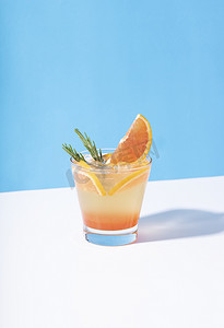橙色清爽背景摄影照片_冷而清爽的橙色潘趣鸡尾酒，颜色背景上有橙色切片。