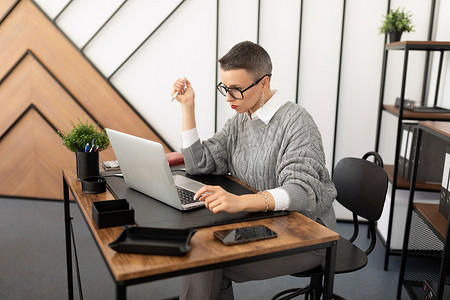一家公司办公室工作人员的肖像，坐在台式机前，拿着笔记本电脑
