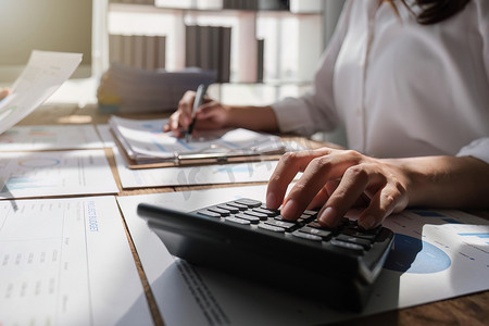 男女会计师使用计算器计算公司财务业绩，并通过财务和分析研究、收入、税收和业务增长的数据网络连接