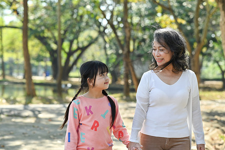 可爱的小孩和年迈的祖母在公园散步，一起在户外度过时光。