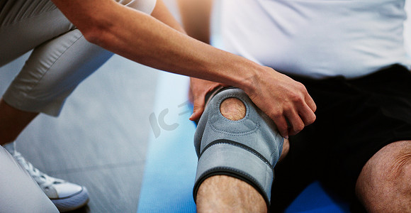 长款包腿护膝摄影照片_物理治疗师的手、护膝和受伤、疼痛和肌肉撕裂的人。