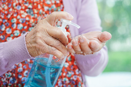 消毒凝胶摄影照片_亚洲老年妇女按蓝色酒精消毒凝胶洗手保护感染冠状病毒。