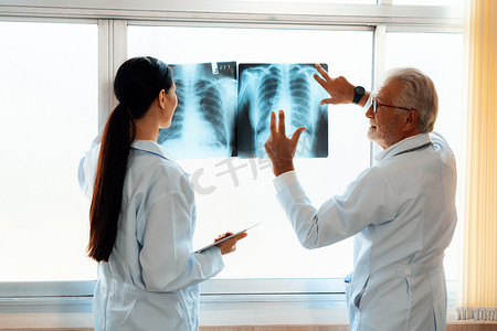 无菌室摄影照片_两名医生在无菌室检查 X 光片以进行医学 X 光诊断。