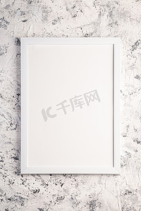 白色带纹理的背景摄影照片_带纹理的明亮灰色背景上的白色空模板画框