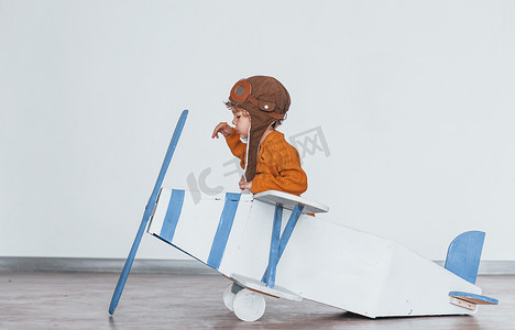穿着复古飞行员制服的小男孩在室内玩玩具飞机