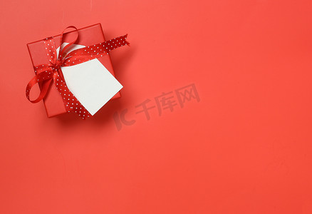 红色礼盒、红点丝带和红色背景上的空白标签的顶部视图 — 情人节、生日、周年纪念