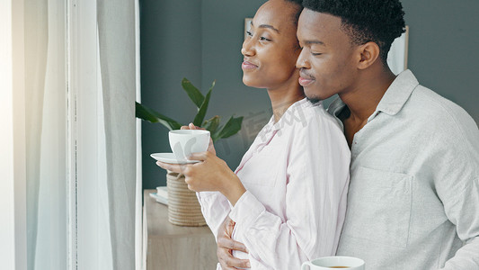 黑人夫妇拥抱和早上喝咖啡，同时表达爱意和关怀，并在度蜜月假期时看着窗外的景色。