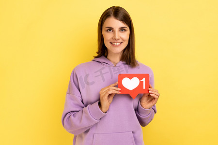 开朗无忧无虑的女人拿着社交媒体的 Heart Like 图标，跟随通知按钮。