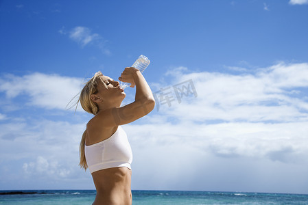 女人在海滩上喝水。