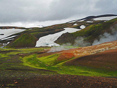 冰岛 Landmanalaugar 山冒着热气的地热河溪流，有郁郁葱葱的绿色苔藓和雪​​洞