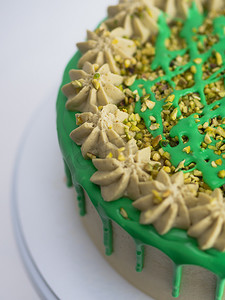 绿色开心果磨砂滴糖霜杯形蛋糕，顶部有糖屑