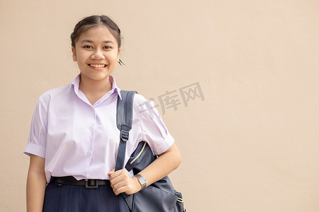 写相册优美文字摄影照片_亚洲女学生穿着制服开心地笑着，带着袋子看着相机，上面有文字空间。