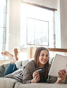 数字平板电脑、信用卡和坐在沙发上的女人，一边放松一边进行网上购物、电子商务和支付。